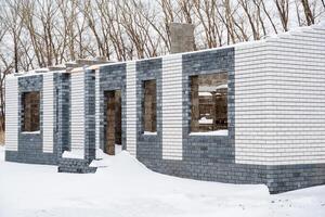 A large brick building, featuring many windows, is presently covered by a thick layer of glistening snow, crafting a stunning winter scene amidst the frigid temperatures of the cold season photo