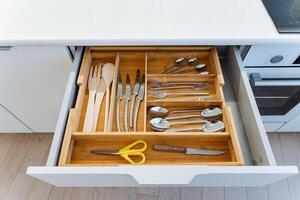 The kitchen drawer is neatly organized with different utensils and scissors, displaying a mix of Wood, Metal, and Rectangular shapes, creating a harmonious combination of materials photo