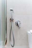 Common fixtures in a bathroom include a toilet and a wallmounted shower head which are essential for its functionality. Plumbing is crucial for ensuring fluid flow in the household photo