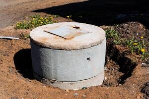 At the construction site, a concrete utility manhole cover is surrounded by wildflowers as part of an urban civil engineering project for infrastructure development photo