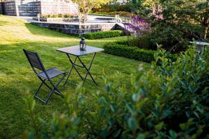 A charming outdoor garden setting featuring a table and chairs, elegantly surrounded by lush greenery and vibrant flowers, invites relaxation photo