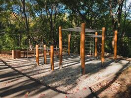 A beautifully crafted wooden playground is situated within a lush park that features trees in the background, providing a delightful natural setting for children to play and explore photo