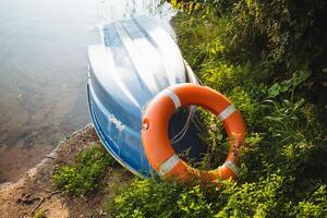 A bright orange life preserver is positioned on the edge of a boat for quick access, ready to ensure the safety of those enjoying their time on the water in case of an emergency photo