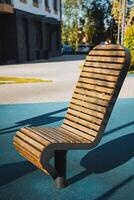 A beautifully crafted wooden chair, elegantly designed, sits on a vibrant blue carpet in front of a charming building, creating an inviting atmosphere for leisure and relaxation photo