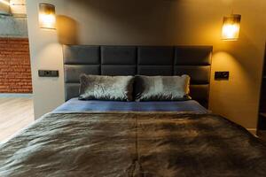 The room boasts a bed, a brick wall, wood flooring, a hardwood door, and a stained ceiling, all designed with a touch of interior design, creating a cozy and stylish ambiance photo