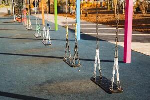 In a lively park, a colorful row of swings is perfectly lined up, ready for children to enjoy their playful moments, surrounded by the beauty of nature and recreational activities photo