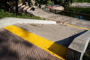 There exists an accessible pathway, complete with bright yellow safety markings, located close to a beautiful scenic waterfront area photo