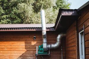 A sturdy metal pipe is securely attached to the side of a wooden house, contributing to the overall structure and functionality of the building while enhancing its aesthetic appeal photo
