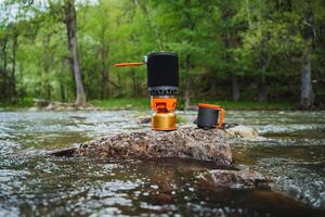 A stove sits precariously on a rock in the river, surrounded by flowing water and the beauty of nature, creating a unique juxtaposition of the manmade and natural elements photo