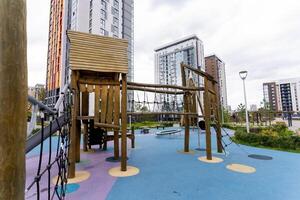 The modern playground structure is beautifully surrounded by highrise residential buildings, creating a vibrant urban play space photo