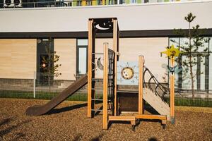 There is a vibrant playground featuring a colorful slide and sturdy stairs situated right in front of a large building, providing a fun outdoor space for children to enjoy photo