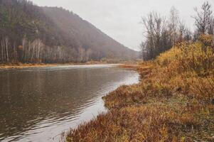 River flowing through mountains and trees under a cloudy sky photo