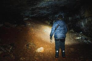 In a pitchblack cave, a courageous person remains steadfast, illuminating the fascinating beauty lurking within the shadows, thanks to the powerful beam of their bright flashlight photo