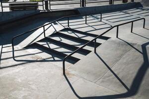 A sturdy railing gracefully casts artistic shadows on the textured concrete surface below, showcasing the beautiful blend of light and form that captures the vibrant essence of urban life photo