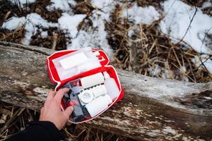 A person is holding a first aid kit securely in their hand, ready to assist in any emergencies that may arise while enjoying their time outdoors. Safety is important in any adventure photo