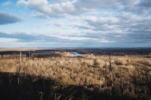 Clouds hover above a river and trees in a natural landscape with grassland photo