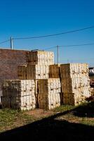 In a vast field, a stack of wooden crates is meticulously arranged, forming a structured heap. Each crate is placed carefully on top of the other, creating a precise and organized pile photo