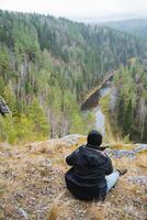 Enjoying a peaceful contemplative moment by the river while overlooking a beautiful forested valley, surrounded by stunning nature photo