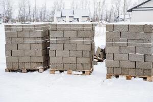 Three large pallets of bricks are carefully stacked on top of one another amidst the cold and snowy landscape, creating a noticeable contrast against the white winter scenery photo