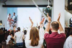 Crowd raising hands in gesture of fun at entertainment event with large screen photo