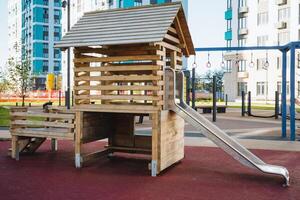 In a bustling playground, there is a beautifully crafted wooden playhouse complete with a fun slide for children to enjoy their time outdoors and have endless fun and laughter photo