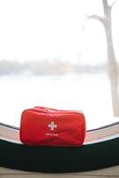 A bright red first aid kit is strategically placed on the window sill to ensure its easily visible and readily accessible during any emergencies that may unexpectedly arise in the house photo