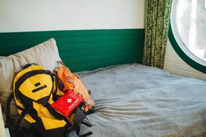 A neatly made bed is adorned with a stylish designer backpack and a wellstocked first aid kit gracefully resting on top, perfectly prepared for any adventure or emergency that may arise photo