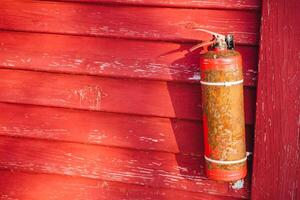 A vibrant red fire extinguisher is prominently hanging on a striking red wooden wall, creating a visually appealing contrast and serving an important safety function in the space photo
