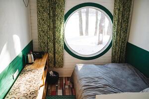This beautifully designed bedroom has a cozy bed with soft linens and a charming round window, creating an inviting and tranquil space ideal for relaxation after a long day photo