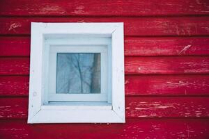 There is a white window that is placed on a bright red wall, creating a striking contrast that catches the eye and adds visual interest to the overall design of the space photo