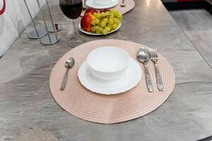An elegantly arranged dining table showcasing exquisite plates, beautifully crafted bowls, shiny spoons, and a lovely glass of wine, all prepared for a truly delightful dining experience photo
