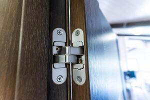 Here is a closeup view of a modern door hinge on a wooden door, showcasing its sleek and stylish design that enhances functionality photo