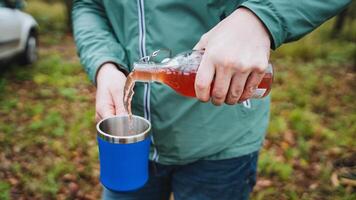 A person is pouring a refreshing drink from a bottle into a cup, showcasing a fluid motion influenced by the gesture of their hand, fingers, and thumb as they serve the beverage photo
