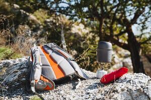 A sturdy backpack is resting atop a large rock near a glowing lantern photo