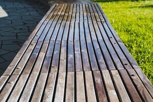 A beautiful, sturdy wooden bench is sitting comfortably in the lush green grass of a serene park, inviting visitors to take a moment to relax and enjoy their surroundings photo