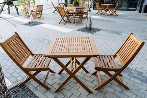 Outdoor furniture set with wooden table and chairs on a brick sidewalk photo