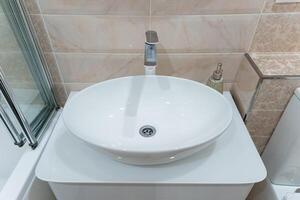 This is a modern white round bathroom sink featuring a sleek faucet, perfectly designed for a contemporary setting and elegant decor photo