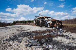 An accident on the road, a car burned to the ground, shelling of a vehicle, a battlefield, a burned-out car. photo