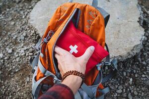 A dedicated hiker is thoroughly preparing for an exciting outdoor adventure, ensuring they have a first aid kit safely packed in their backpack photo