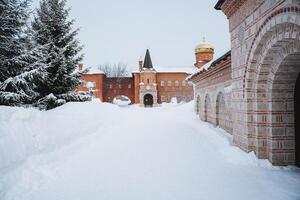 a snowy path leading to a brick building with a tower in the background photo