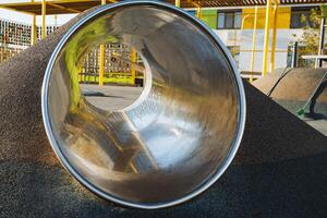 In a childrens playground, theres a metal tube that features a hole located right in the center of it, providing space for various activities and imaginative play. Its a fun addition photo