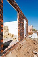 Construction site with brick wall under clear sky showing incomplete building structure in progress, showcasing construction and development work in urban setting photo