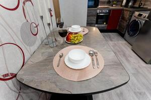 In a cozy kitchen, a carefully arranged table featuring plates and utensils helps to create a warm and inviting atmosphere that draws you in, making you feel right at home and relaxed photo