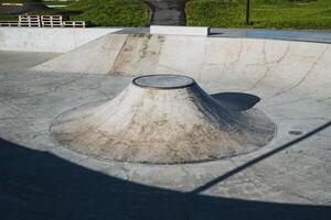 The skate park features a distinctive coneshaped ramp positioned right in the center, surrounded by smooth asphalt and grass, making it an ideal place for skaters and enthusiasts to enjoy photo