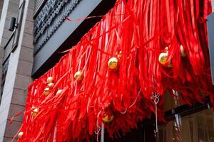 A beautiful building, adorned with vibrant red ribbons and shimmering gold balls hanging elegantly from its exterior, creating a festive atmosphere and celebrating a special occasion photo