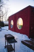 A vibrant red building with round windows features captivating architecture. Its beautifully designed front grill enhances the outdoor space, perfect for gatherings and social events photo