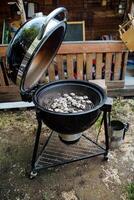 An open charcoal grill with hot coals ready for grilling, set in a rustic outdoor setting. The smoky aroma and sizzling sounds enhance the summer barbecue experience photo