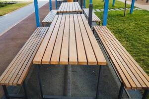 A long wooden picnic table with benches in a park photo