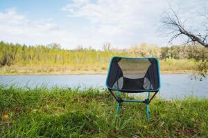 Imagine a portable camping chair by a tranquil river the perfect spot for relaxation, surrounded by natures beauty and serenity photo
