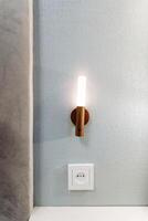 There is a bright light positioned on the wall right next to an electrical socket that is installed in the room, illuminating the area around it and enhancing the overall ambiance photo